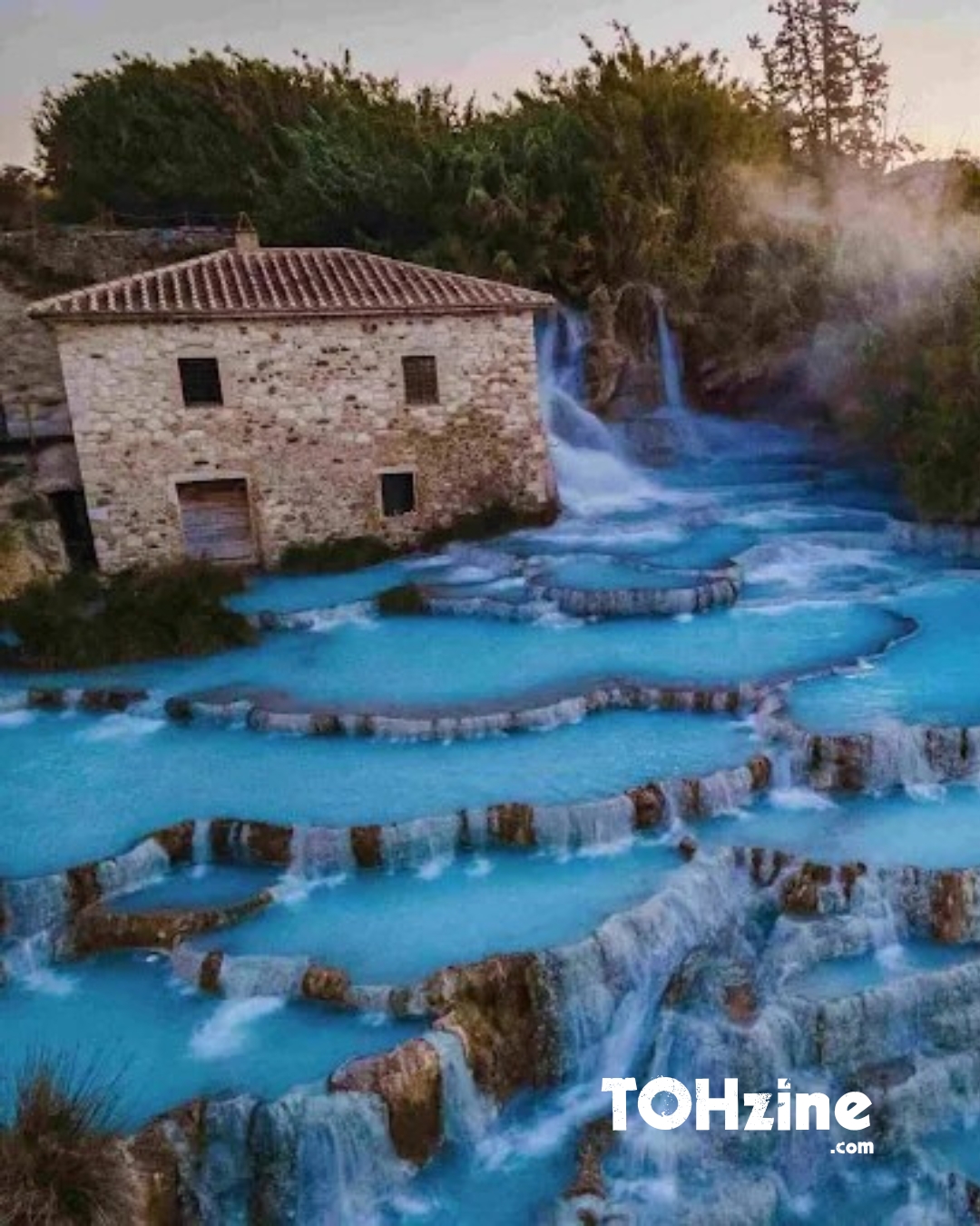 Cascate del Mulino a Saturnia, vasche di acqua termale azzurra e casale in pietra al tramonto